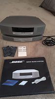 Front view of Bose Wave Music System with two remote controls, power cable and instruction manual