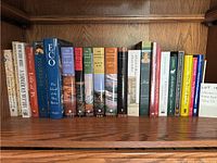Books arranged on a wooden shelf showing titles and spines