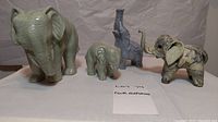 Four small elephant figurines displayed on white background, showing overall collection