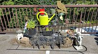 Main overview of the large metal garden stand with various pots, watering can, and garden figurines on the balcony patio.