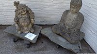 Both Buddha statues displayed side by side on stone slabs against exterior wall