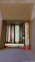 Photo of the open box of assorted hardcover war books mostly about the Civil War with visible titles including Churchill, New York Times Civil War, Theories For Everything.