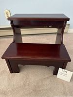 Front view of two-step wooden step stool with cherry finish, showing both steps and curved side supports.