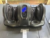 Front view of the foot massager showing two large foot compartments and central control panel with blue digital display lighted up.