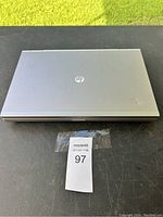Closed gray HP laptop showing small dent on upper right corner of top lid