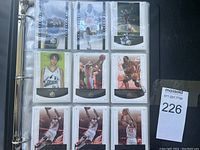 Photo of multiple basketball cards in binder plastic sleeves, showing various NBA players in action poses, predominantly from SP Authentic series.