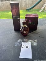 Round, faceted purple glass perfume bottle with gold and purple square cap, displayed with its hammered textured purple box labeled 'Jimmy Choo Fever'.