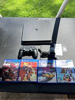 Overhead view of PS4 Slim console, controller, power cable, and four game cases