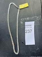 Full view of the silver thick mariner chain necklace with original price tag and lot number for auction.