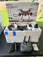 Complete drone set including original box, drone in foam packaging, remote controller, and accessories laid out on table.