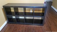 Front view of the black wooden cubby cabinet showing 8 compartments and overall structure.