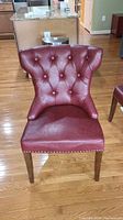 Front view of the merlot-colored Pier 1 accent chair showing button tufted back and seat with slight distressed leather and wooden legs.