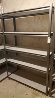 Full view of metal shelving unit with four white veneer shelves in basement setting