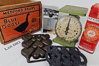 All items grouped showing crate, scale, molds, can opener and a red tin beside them