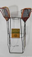 Foldable metal wire display holding two fly swatters with wooden frames and wire mesh heads, featuring a cardboard ad sign for Gatch Swatters at 10 cents.