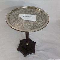 Full view of the Bombay pedestal table showing the engraved metal tabletop and wooden column base with hexagonal wooden platform base.