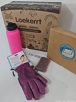 Full view of lot items including boxed espresso maker, water bottle, box of Pistachio Pedestal, Scrubbee gloves, and chain mail scrubber.