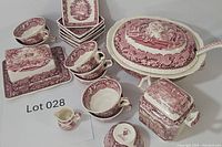 Full lot showing tureen with ladle, butter/cheese dish, square bowls, cups, and creamer in red transferware pattern.