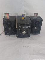 Full view of the Sharp mini component system with the central unit and two speakers arranged, three cassette tapes placed on top of units.