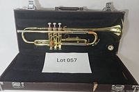 Full view of Yamaha trumpet placed inside its black lined and brown exterior case labeled Lot 057.