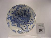 Front view of the round porcelain side plate showing detailed blue dragon decal design with decorative swirls and clouds.