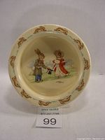 Overhead view of the bowl's interior showing the central image of two rabbits in period clothing with the text 'The Proposal' beneath, surrounded by rabbit motifs around the inside rim.