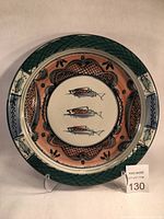 Front view of large white stoneware platter with painted fish and geometric designs