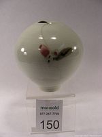 Front view of rounded pale green celadon porcelain vase with copper red and tomaku brush decoration.