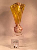 Full view of the yellow glass vase showing ruffled top and swirling colored ribbons.