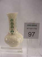 Front view of ivory porcelain vase showing green shamrock decoration and raised relief design.