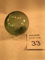 Front view of emerald green spherical glass fishing float showing bubbles and impurities.