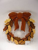 Top view of handcrafted wooden Christmas wreath showing holly leaves, berries, and bow in various shades of wood with semi-matt finish.