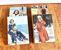 Photo of four vintage 1975 and 1976 Eaton's and Sears catalogs arranged on wooden floor, featuring fashion covers with women models in winter wear.