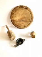Full set of four items shown from above including round wooden bread board with 'Bread' carved, honey dipper, tin pastry decorator, and butter press.