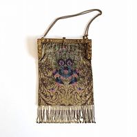 Full view of large antique beaded purse showing metal frame, floral beadwork, chain handle, and beaded fringe at bottom