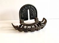 Front angled view showing the semi-circular iron rack with wooden finger slots and the curved back plate with mounting slit.