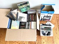 Complete lot shown with boxed plastic container holding CDs and cassette tapes, Sony Walkman in original packaging, headphones and manuals.