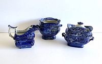 Photo showing all three flow blue pieces: creamer, two sugar bowls (one missing lid).