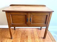 Front view of the vintage wooden 2 door cabinet showing its rectangular shape, two paneled doors, and backsplash at the back