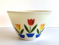 Side view of large ivory Fire King mixing bowl showing colorful tulip flower design on exterior.