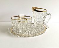Overall set showing pitcher, four glasses, and tray with raised thumbprint design and gold rims