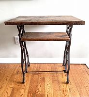 Front view of vintage sewing stand with barnboard top and lower shelf on iron frame, showing overall structure and proportions.
