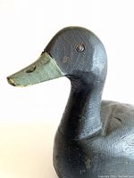 Close-up front and side view of wooden duck decoy head showing tack eyes and painted beak