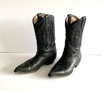 Front angled view of both black leather cowboy boots showing the pointed toes and decorative stitching on the shafts.
