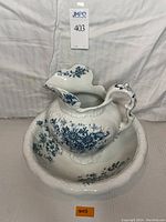 Porcelain wash basin and pitcher set with dark blue floral pattern, viewed front with pitcher inside basin.