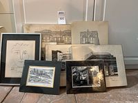 Eight black and white framed and unframed pieces arranged on floor