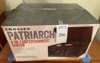 Photo of the boxed Crosley Patriarch 4-in-1 Entertainment Center showing the brand and model on the packaging.