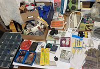 Photo of assorted household tools and hardware items including organizers, gloves, rotary tool accessories, drill bit sets, safety lights, and power strips.