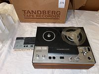Tandberg Series 3000X reel tape recorder unit with one reel installed and original box behind on white surface