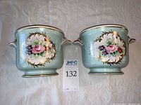 Pair of blue hand painted Limoges planter pots with gold and floral accents, front view showing matching designs on each pot.